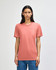A coral American Apparel Tri-Blend T-Shirt on a model, featuring a crew neck and short sleeves. The shirt has a logo.