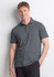 A man wearing a grey short sleeve polo shirt, standing casually with a friendly expression. The shirt has a collar and branding.