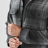 A men's shacket in a black and grey Highland plaid pattern, featuring button pockets and long sleeves.
