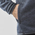 A grey polar fleece jacket featuring a side pocket and a fitted design at the cuffs. It has a logo on the hem.
