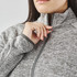 A close-up of a woman's neck and shoulder wearing a grey full zip fleece jacket with a high collar.