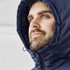 A man wearing a navy thermal puffer jacket with a hood, featuring a logo on the chest.