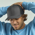 A grey trucker cap with a mesh back, worn by a smiling man in a light blue sweatshirt.