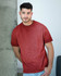 A man leans against a concrete pillar, wearing a maroon Colortone® Oil Wash T-Shirt. The shirt has a casual, relaxed fit.