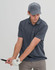 A grey Jacquard Texture 5 Panel Cap worn by a man swinging a golf club, with a logo on the cap.