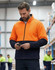 A Hi-Vis polar fleece full zip jacket in bright orange and navy, worn by a man using a phone.