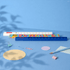A 30cm popper ruler in blue with a colourful design, surrounded by stationery items like paperclips and circular paper.