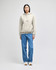 A model wears a beige Champion Reverse Weave® hooded sweatshirt paired with blue jeans. The sweatshirt features a logo.