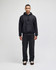 A black pullover hooded sweatshirt worn with matching dark trousers, featuring a logo on the sleeve.