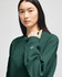 A model wearing a dark green Champion Reverse Weave® adult crew sweatshirt featuring a logo on the sleeve.