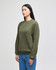 An olive green crewneck sweatshirt displayed on a model, featuring a logo on the sleeve.