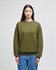 An adult crewneck sweatshirt in olive green, featuring a logo and styled with blue jeans.