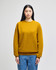 A mustard yellow adult crewneck sweatshirt with long sleeves, featured on a model wearing jeans. The sweatshirt has a logo on one sleeve.