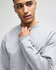 A grey Champion Powerblend® adult crewneck sweatshirt with a logo detail on the sleeve, displayed by a model.