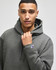 A grey sweatshirt with a hood, featuring a logo on the sleeve, worn by a model.