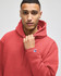 A red crewneck sweatshirt worn by a model, featuring a logo on the sleeve.
