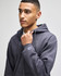 A grey Champion Powerblend® adult crewneck sweatshirt is worn by a person. The garment has a hood and a logo on the sleeve.