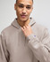 A man models a taupe Champion Powerblend® adult pullover hooded sweatshirt with a logo on the sleeve.