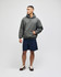 An adult pullover hooded sweatshirt in green, paired with navy shorts. The model stands confidently with one hand in the pocket.