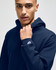 A navy blue hooded sweatshirt with a logo on the sleeve, featuring a model wearing it.