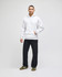 A white pullover hooded sweatshirt worn with dark jeans and trainers, featuring a logo on the garment.