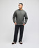 A man stands wearing a grey pullover hoodie, paired with black pants, showcasing a simple and casual style.