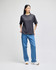A grey T-shirt displayed on a model, paired with blue jeans. The shirt features a logo.