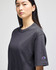 A dark grey Champion Adult Heritage Jersey T-Shirt displayed on a model, featuring a logo on the sleeve.