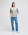 A grey Champion Adult Heritage Jersey T-Shirt worn with blue jeans, featuring a casual style and relaxed fit.