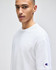 A white Champion adult heritage jersey t-shirt displayed on a model, featuring a logo on the sleeve.