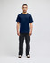 A model wearing a navy blue short-sleeve t-shirt and black pants, featuring a branding logo.