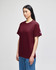 A maroon short-sleeve t-shirt displayed on a model, featuring a logo on one sleeve.