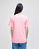 A pink short-sleeve t-shirt viewed from the back, featuring a logo. The wearer has long hair and is dressed in blue jeans.
