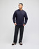 A model in a navy short-sleeve t-shirt paired with black trousers and brown shoes, featuring a logo on the sleeve.