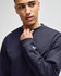 A navy blue Champion adult short-sleeve t-shirt with a logo on the sleeve. The model is thoughtfully posing.