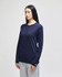 A long-sleeve t-shirt in navy blue with a logo, worn by a model alongside grey pants.