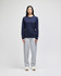 A long-sleeve navy T-shirt displayed on a model paired with grey sweatpants and white sneakers. The shirt features a logo.