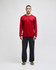 A red long-sleeve t-shirt on a model, paired with dark trousers and green shoes. The shirt features a logo.