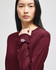 A maroon long-sleeve t-shirt with a branding logo on the sleeve. The model is facing forward.