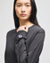 A long-sleeve t-shirt in dark grey with a logo on one sleeve, modelled by a woman.