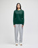A long-sleeve green t-shirt worn with grey sweatpants. The t-shirt features a logo on the sleeve.