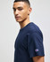 A navy short sleeve t-shirt featuring a logo on the sleeve. The model is facing sideways.