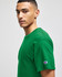 A green Champion adult jersey short sleeve T-shirt displayed on a model, featuring a logo on the sleeve.