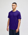 A purple Champion adult jersey short sleeve T-shirt displayed on a male model, featuring a logo on the sleeve.