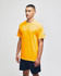 A yellow short sleeve t-shirt with a logo, worn by a model, paired with navy shorts.