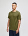 A green Champion adult jersey short sleeve T-shirt displayed on a model, featuring a logo on the sleeve.
