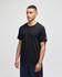 A black short sleeve t-shirt with a logo on the sleeve, displayed by a model standing against a neutral background.