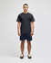 A model stands wearing a grey short sleeve t-shirt and navy shorts, featuring a logo on the shirt.