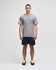 A model wearing a grey short sleeve t-shirt and navy shorts, featuring a logo on the t-shirt.