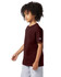 A burgundy short sleeve T-shirt for youth with a logo on the sleeve, displayed on a child with curly hair.